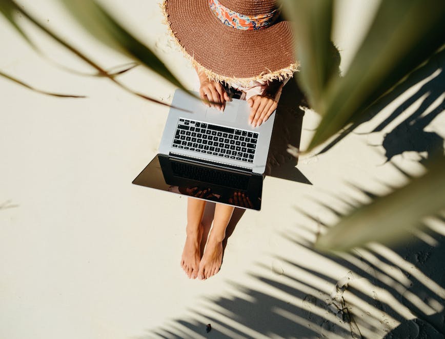 Frau mit Laptop unter Palmen am Strand